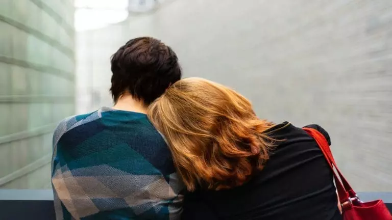 a woman rests her head on another person's shoulder