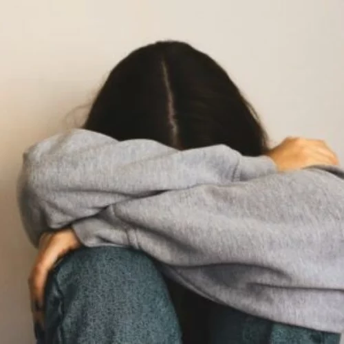 a woman sitting on the floor with her arms wrapped around her head